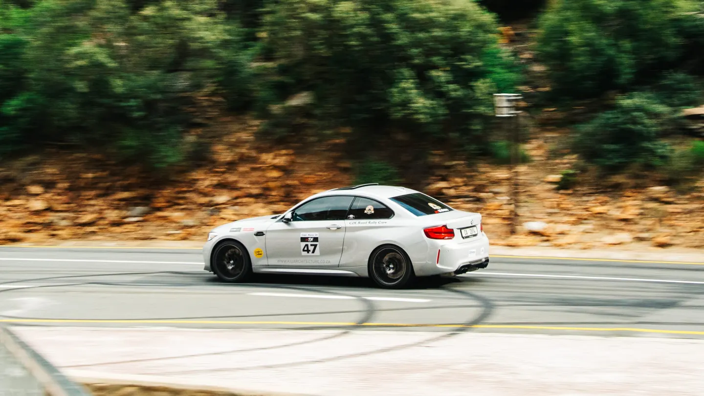 A white BMW M2 wearing rally number 47 at speed
