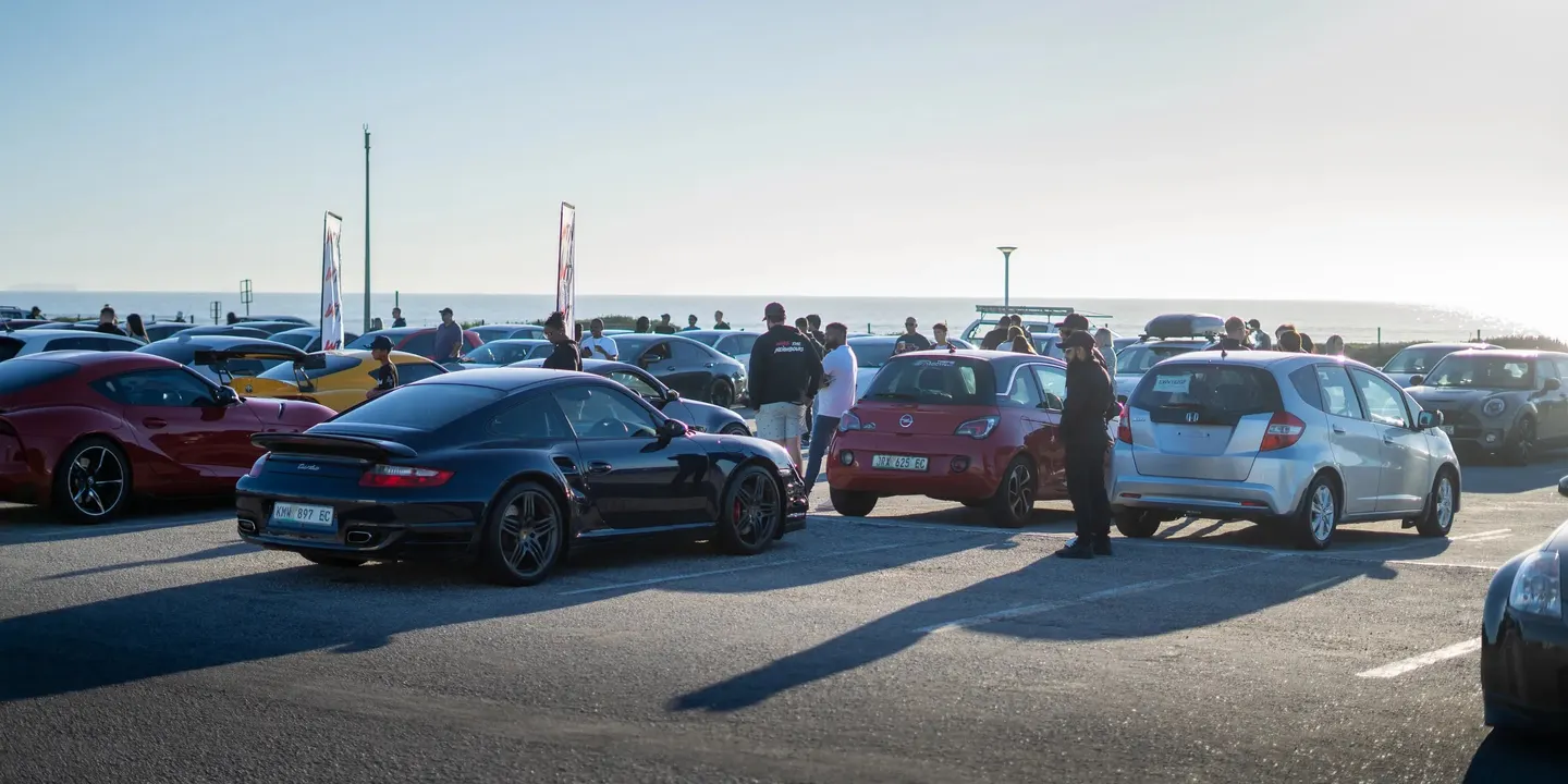 A black Porsche 911 Turbo among the cars at a WTN meet by the sea
