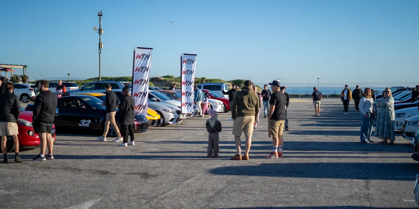Drivers and cars gathered under WTN flags by the sea