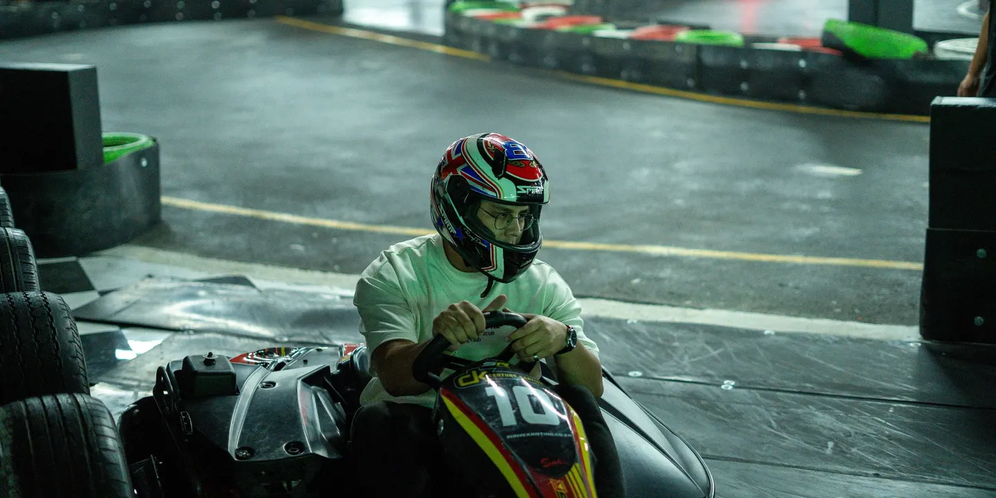 A driver in a helmet leaning into a corner at Century Karting