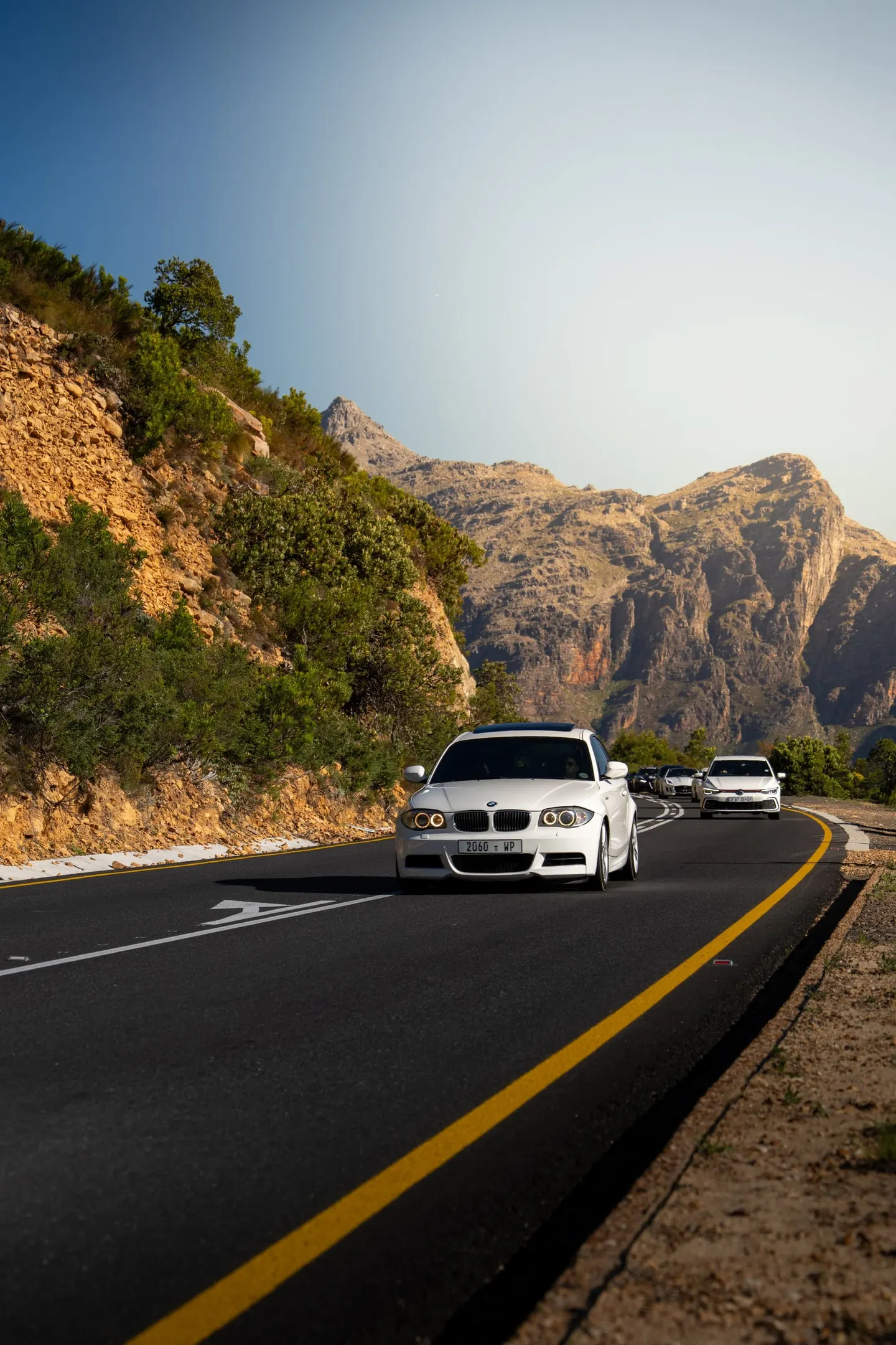 A white BMW leading the group through the last of the light
